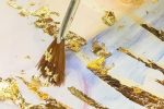 how to use gold leaf. Gold leaf being applied with a brush.