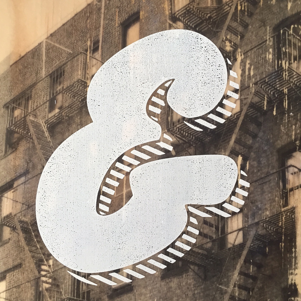 Ampersand screen printed into a black and white photo printed on a block of wood.
